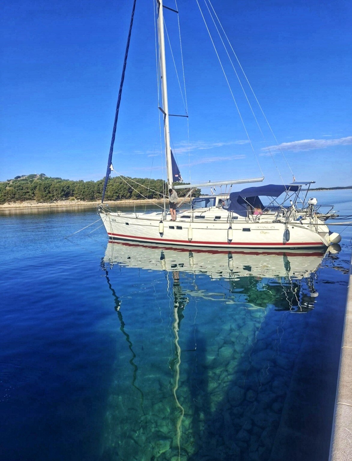 Sailing yacht reflected in crystal-clear water